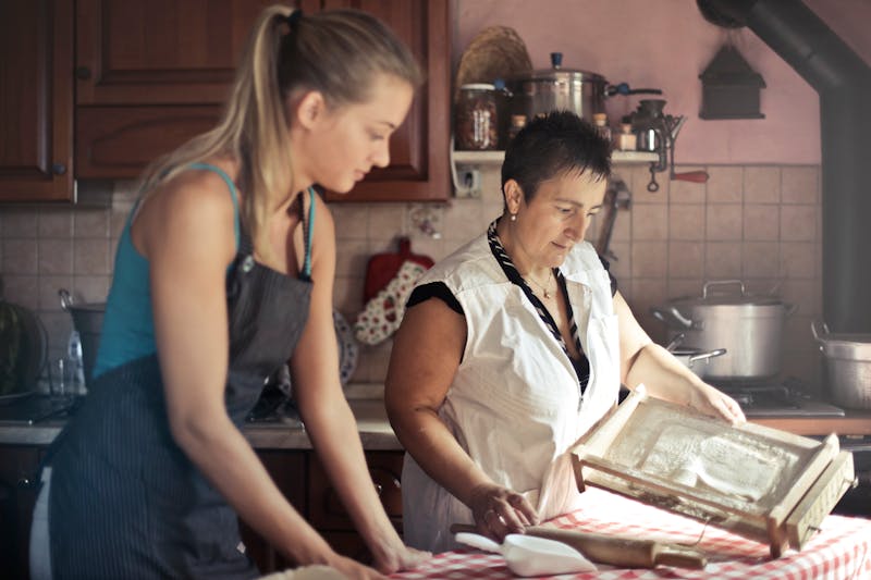 Mother teaching her daughter to bake in the kitchen, measuring ingredients together — a practical way to learn fractions and measurement